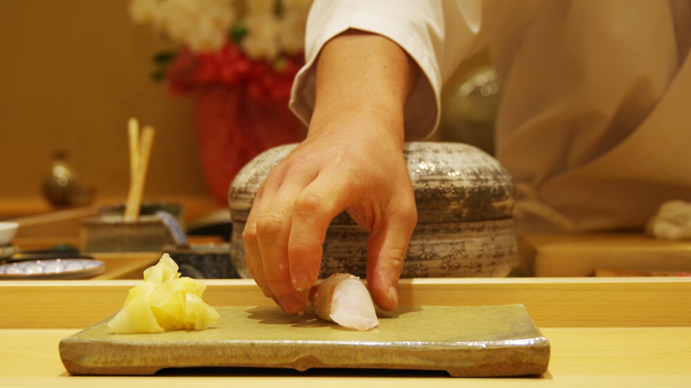 sushi chef serves suchi