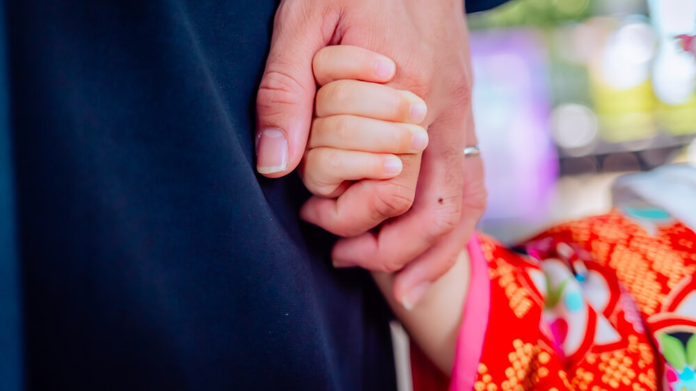 a child hold her father's hand