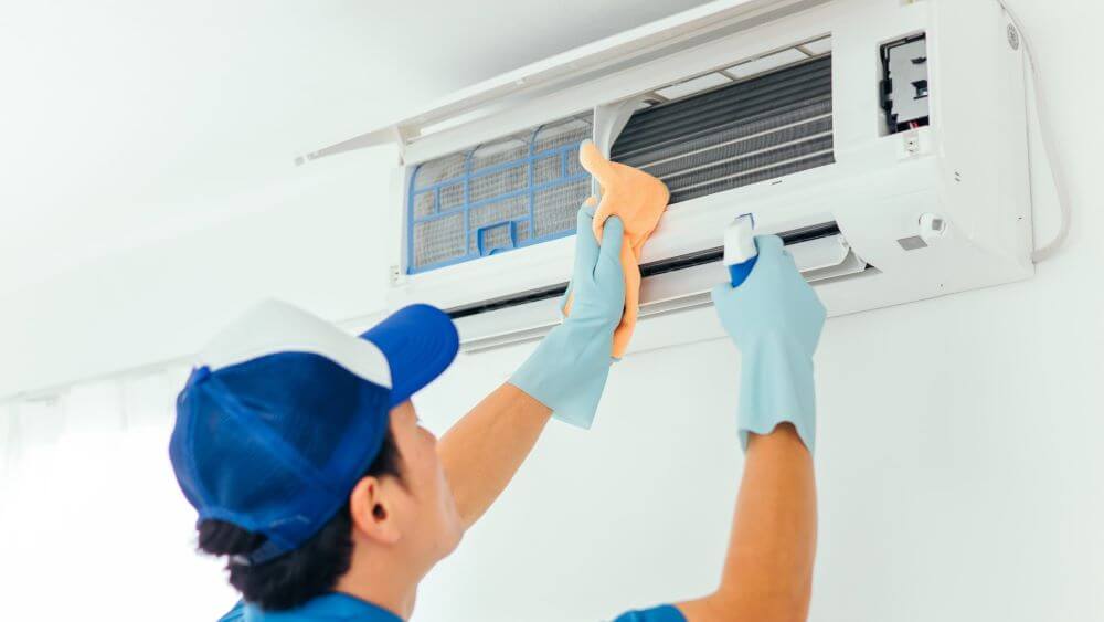 a guy clean an air conditioner